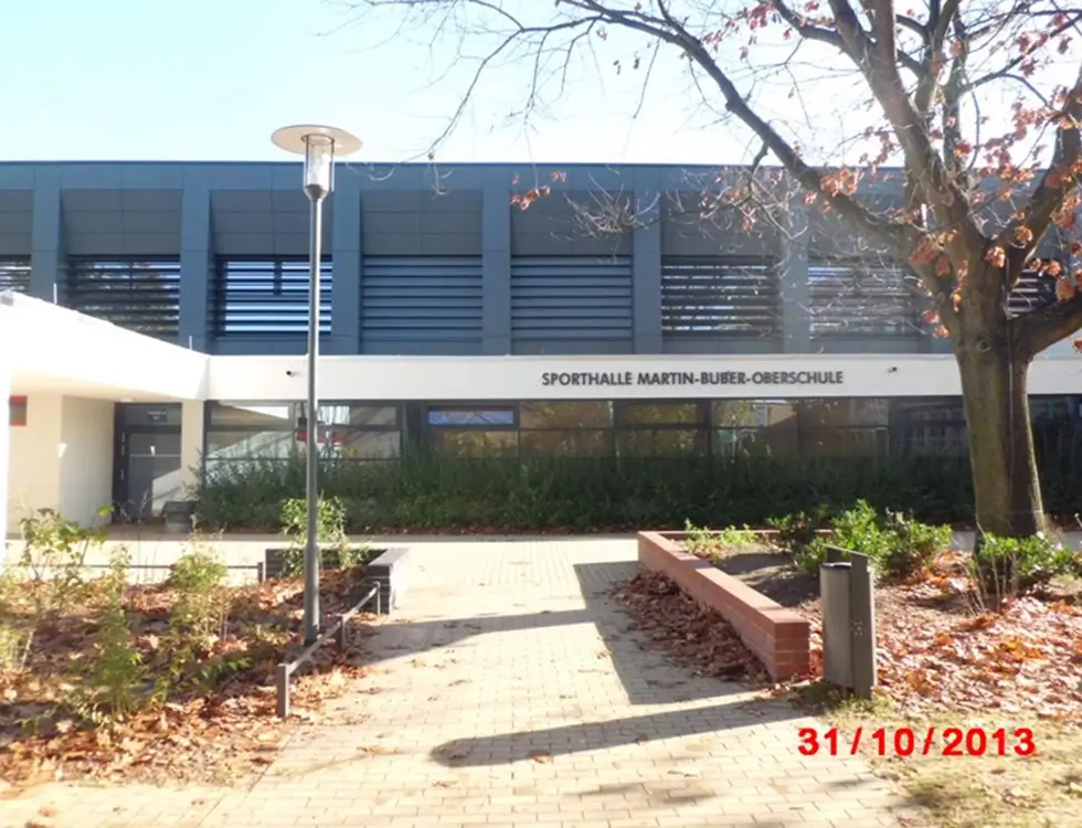 Grauer Fassadenbau einer Sporthalle auf einem Schulgebäude